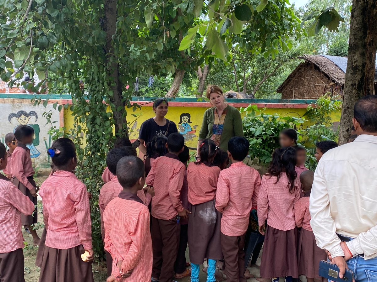 Jenna Davis speaks with students in a courtyard outside of a school.