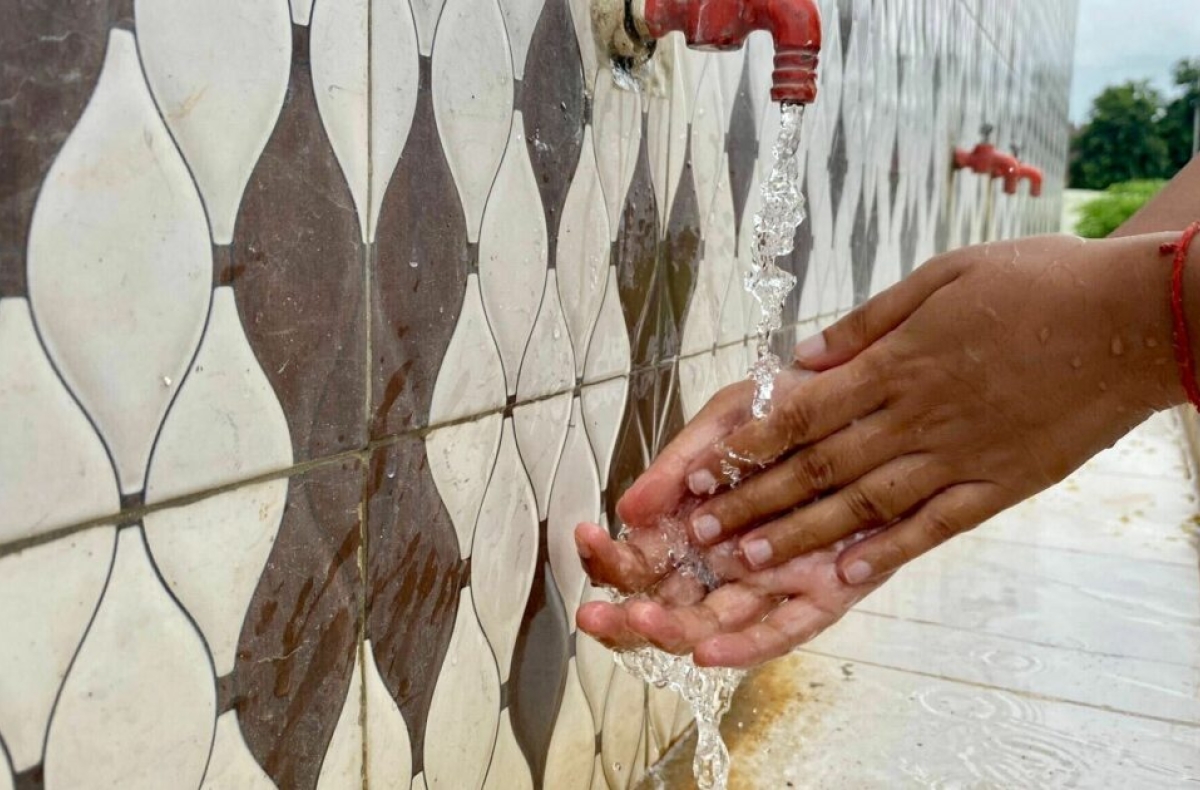 A woman washes her hands at an outside hand-washing station, India