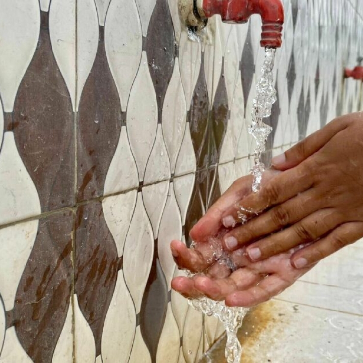 A woman washes her hands at an outside hand-washing station, India